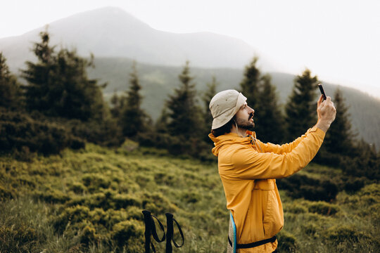 the traveler takes a photo on the phone against the background of mountain landscapes. A tourist is looking for a mobile connection or mobile phone network signal in the mountains