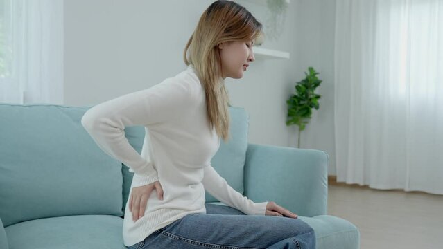Asia beautiful woman holding her lower back while and suffer from unbearable pain health and problems, chronic back pain, backache in office syndrome, scoliosis, herniated disc, muscle inflammation