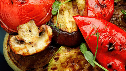 Baked vegetables, tomatoes, eggplant, zucchini, sweet pepper and champignon mushrooms, in a plate. close-up