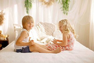 Cute sweet toddler children, tickling feet on the bed, laughing and smiling