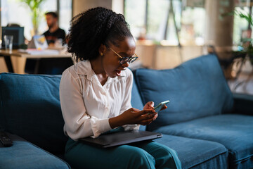 Black businesswoman working on laptop. Portrait of beautiful businesswoman using the phone in the...