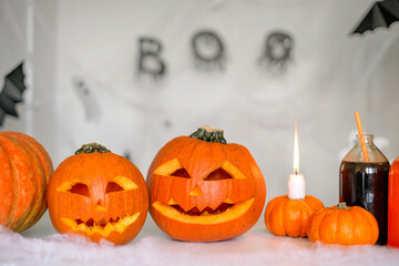 Carved Jack-o'-lantern pumpkins with a magic potion in bottles stand on a table decorated with candles and cobwebs