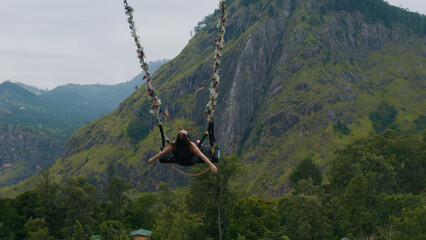 Girl swinging on giant swing against picturesque landscapes of Nuwara Eliya.