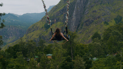 Girl swinging on giant swing against picturesque landscapes of Nuwara Eliya.