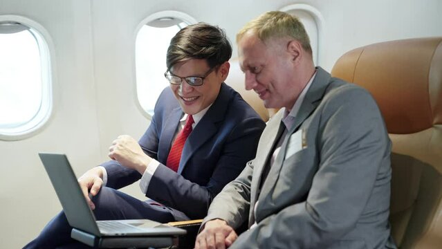 Young Businessman And Senior Using Laptop Sitting Near Window On First Class In Plane During Flight. Passenger Business Partner,  Wealthy Company Executive Travel Working. Traveling And Business.