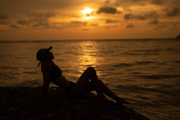 woman silhouette watching sun on the beach at sunset