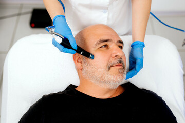 Fototapeta premium Middle aged male client during deep facial cleansing in a cosmetology clinic