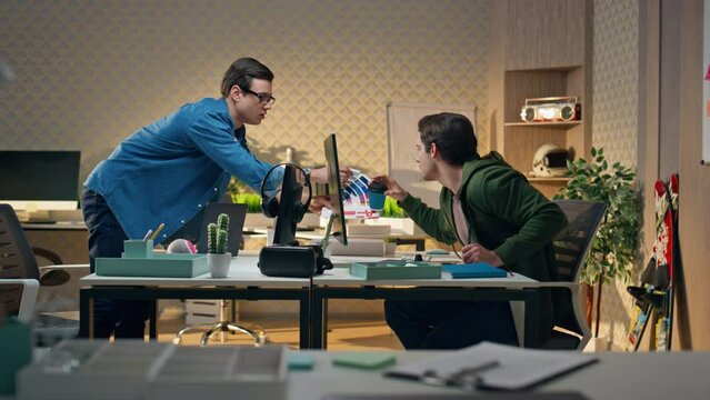 Young creator discussing colour swatches at office. Man showing to colleague guy