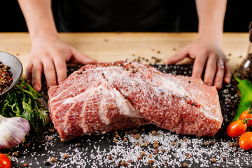 Chef applying grained salt on raw piece of steak. Cooker preparing meat on professional kitchen...