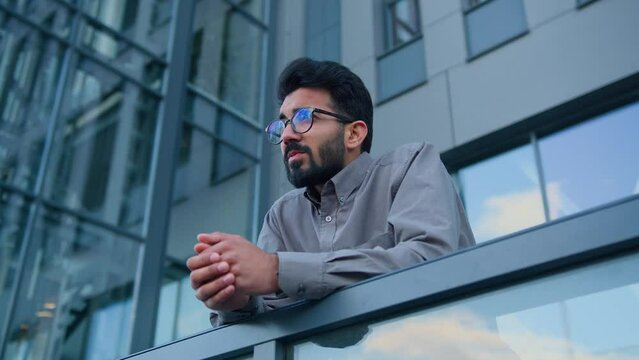 Sad thoughtful man Indian Arabian pensive businessman entrepreneur employer on terrace balcony outdoors depressed upset male worker in city concerned with business failure difficult decision crisis