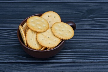 a pile of brown round cookies in a cup stands on a black wooden table