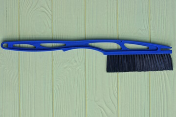 one blue plastic brush broom for cars with black bristles lies on a yellow wooden table