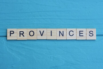 word provinces made of small gray wooden letters on a green blue wood background
