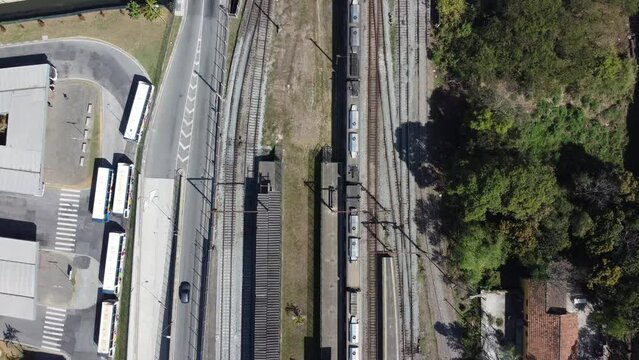 Vis&atilde;o a&eacute;rea de um trem atravessando a ferrovia na cidade de Suzano em S&atilde;o Paulo captada do alto por um drone entre a linha de trem e avenida principal da cidade. 