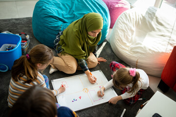 Muslim young teacher with small group of children having school learning - obrazy, fototapety, plakaty