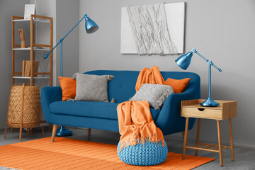 Blue sofa with pillows and orange carpet in living room interior
