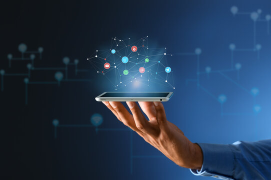 Hand of businessman with tablet computer and digital icons on dark blue background