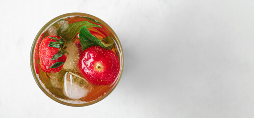 Glass of ice tea with strawberry and mint on light background with space for text, top view