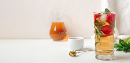 Glass of ice tea with strawberry and mint on white table. Banner for design