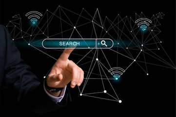 Young businessman with virtual screen using web search engine on dark background