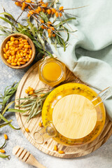 Healthy sea ​​​​buckthorn tea with honey on a gray stone background. Autumn tea, berries seasonal drink. View from above.
