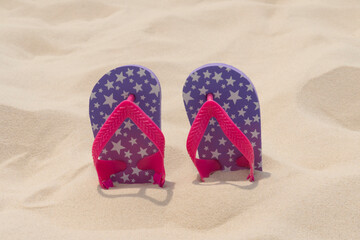 Slippers lie in the sand on the beach. Summer vacation, travel and tourism concept