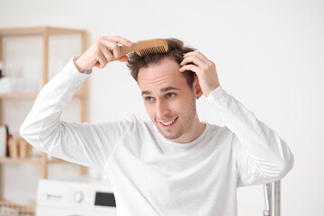 Young man combing hair in bathroom