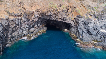 Aerial view of rocky cliffs on the coast of Madeira at the Atlantic ocean with clear blue water