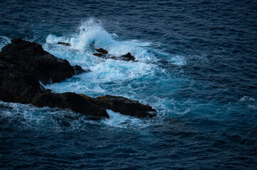 Fototapeta premium Dark dramatic Atlantic Ocean with waves breaking on the rocks dark blue