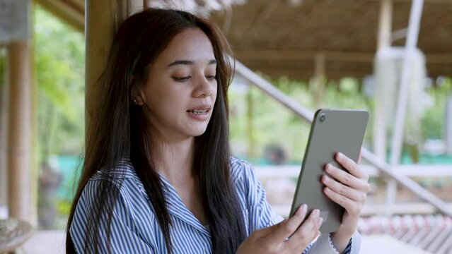 Portrait, Beautiful Asian women hang out on weekends, come out find comfort in natural place, holds up tablet video chat with friends, let friends see where went vacation, smiled brightly.