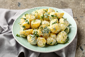 Plate of tasty Potato Salad with greens on grunge background