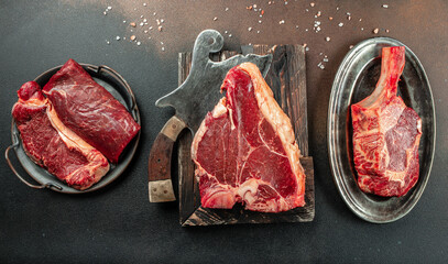 Large raw t-bone steak on a wooden board. Porterhouse steak with a meat cleaver on a dark...