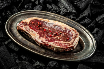 marbled beef New York steak on BBQ grill coal. Fresh meat for grilling. steak raw striploin of beef. top view. place for text