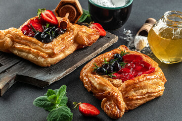 Small open pie made of puff pastry with fresh berries on a dark background, Food recipe background. Close up