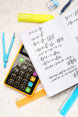 Copybook with maths formulas, calculator and stationery on white grunge background