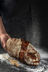Homemade sourdough bread in hand on a dark background. banner, menu, recipe place for text, top view