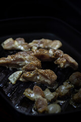 Chicken pieces grilling on a stove.