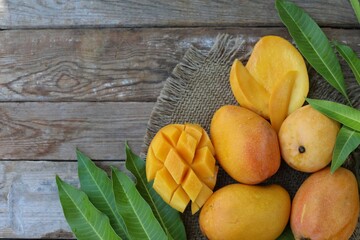 Yellow mango, exotic fruit, pieces of mango, on a wooden background, background image, top view, place for text