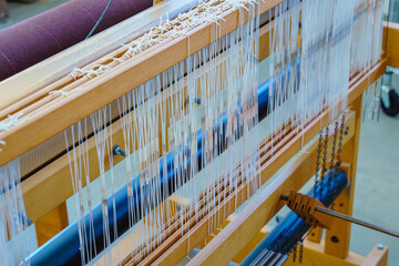Close-up of a floor loom warp threads and heddles for textile weaving - obrazy, fototapety, plakaty