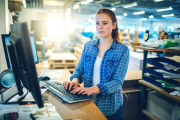 Young woman using a computer while working in a printing press office