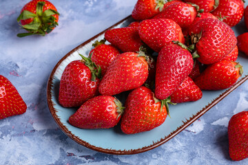 Plate of fresh strawberries on blue background