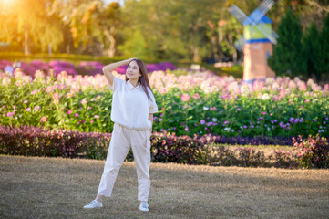 Asian woman standing at the park. Windmill and flower in background