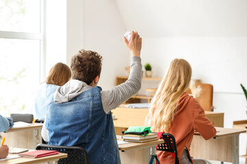 Male student throwing crumpled paper in his classmates at classroom