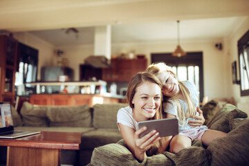 Mother and daughter taking a selfie while playing together on the couch in the living room at home