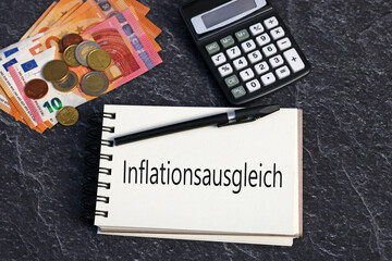 Der Text Inflationsausgleich einem Notizblock mit Eurobanknoten und Taschenrechner.