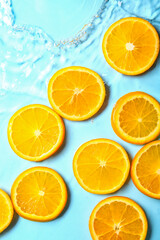 Fototapeta na wymiar Slices of fresh orange in water on blue background