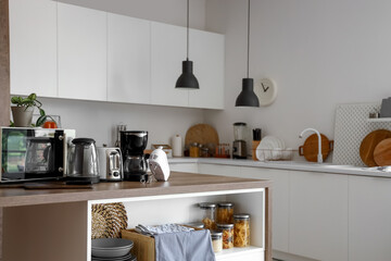 Microwave oven, electric kettle, toaster, coffee maker and mixer on wooden table in kitchen