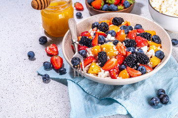 Summer fruit and berry salad with cottage cheese. Big bowl with breakfast or lunch salad with sliced fruits, blueberry, strawberry, blackberry and high-protein curd cheese sauce