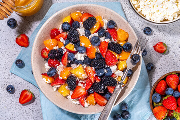 Summer fruit and berry salad with cottage cheese. Big bowl with breakfast or lunch salad with sliced fruits, blueberry, strawberry, blackberry and high-protein curd cheese sauce