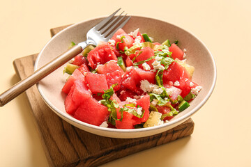 Bowl of tasty watermelon salad on yellow background